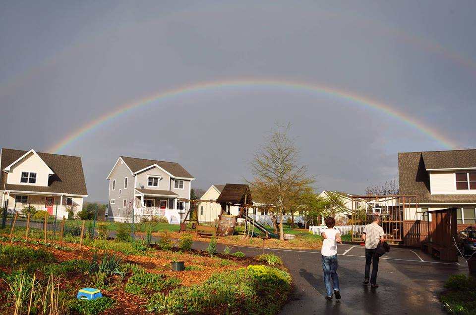 Houses around a garden with a rainbow overtop of houses with gray sky