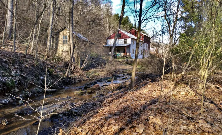 Picture of a creek with a red and white farmhouse in background